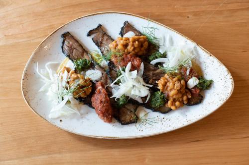a plate of food with meat and vegetables on a table at Hotel Zed Tofino in Tofino