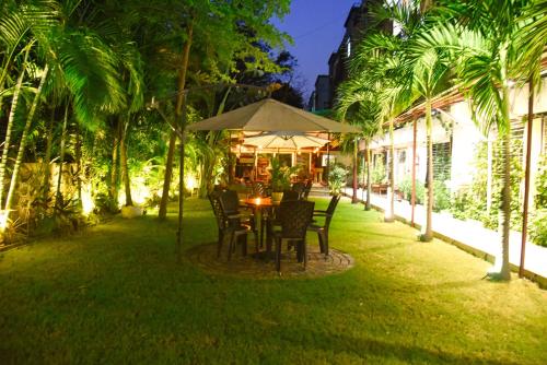 a table and chairs under an umbrella in a yard at Royal Palms Luxury Service Apartment in Nagpur