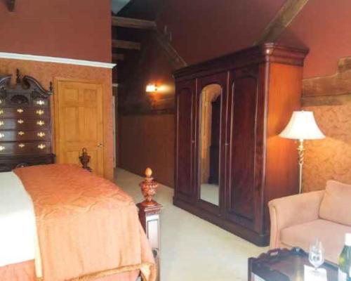a bedroom with a bed and a chair and a dresser at Copper Beech Inn in Ivoryton