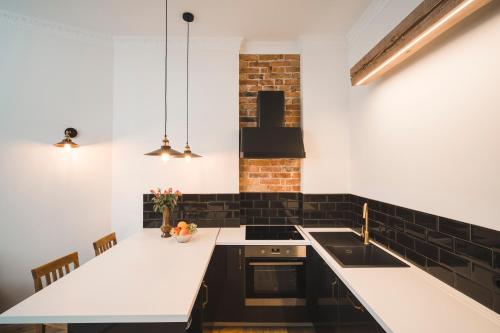 a kitchen with white counters and a brick wall at Berchy Apartment 1 in Liepāja