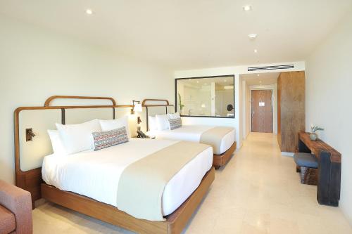 a hotel room with two beds and a desk at Corazón Cabo, a Noble House Resort in Cabo San Lucas