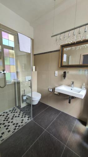 ein Badezimmer mit einem Waschbecken, einem WC und einem Spiegel in der Unterkunft Hotel Osteria Del Vino Cochem in Cochem