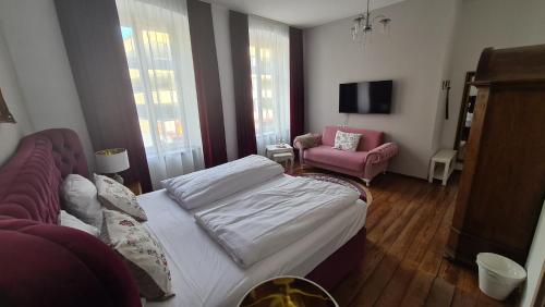 a bedroom with a bed and a pink chair at Hotel Osteria Del Vino Cochem in Cochem
