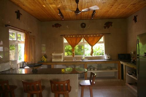 eine Küche mit einem Tisch und Stühlen sowie 2 Fenstern in der Unterkunft Villa Kass in Baie Sainte Anne