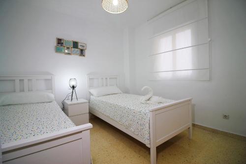 - une chambre blanche avec 2 lits et une fenêtre dans l'établissement Apartment Avenida Miramar, à Fuengirola