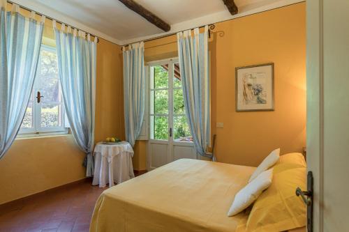 a bedroom with a bed with blue curtains and a window at Il Giardino Inglese in Lucignano