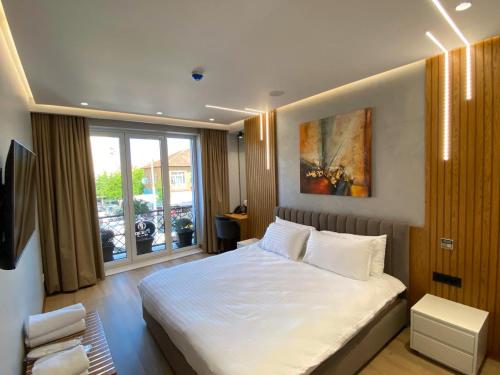 um quarto com uma grande cama branca com janela em Primo Hotel em Tirana