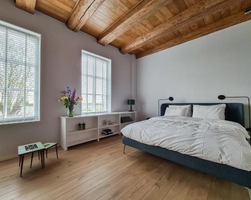 1 dormitorio con 1 cama grande y 2 ventanas en B and Be Happy Friesland, en Lioessens