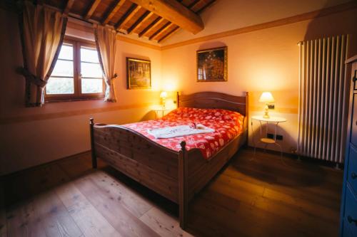 a bedroom with a bed with a red comforter and a window at Borgo 7 TigliAppartamento a Montepulciano n7 in Montepulciano