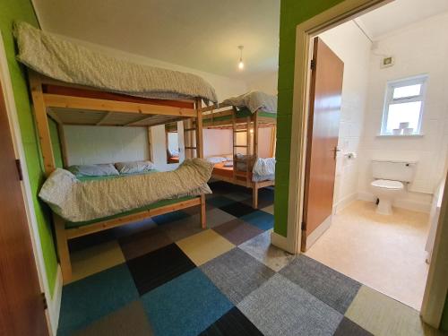 a room with three bunk beds and a bathroom at Basecamp Wales in Llanllyfni