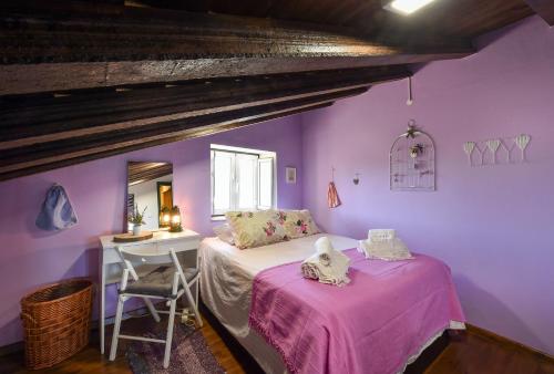 a bedroom with purple walls and a bed and a desk at Casa da Aldeia in Alcaria Ruiva