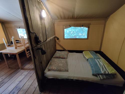 Saint-Saud-LacoussièreにあるCamping de la Bucherieの窓付きの客室の小さなベッド1台分です。