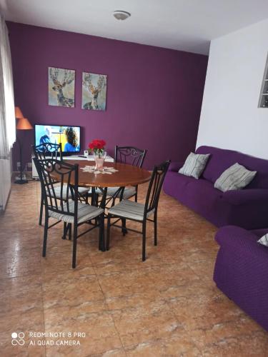 ein Esszimmer mit einem Tisch und einem lila Sofa in der Unterkunft Apartamentos Rurales Hermanos Alcalá in Ibdes