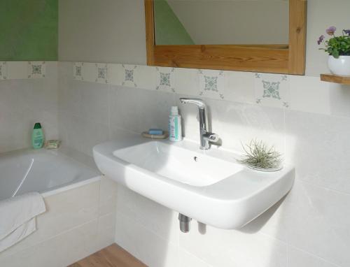 a white bathroom with a sink and a bath tub at Gästehaus Kibbel in Bosau