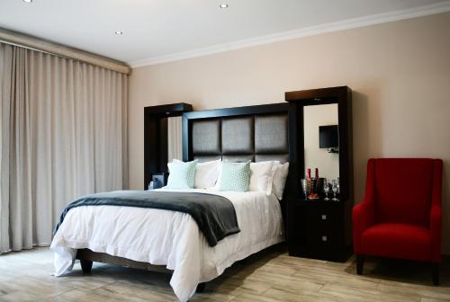a bedroom with a large bed and a red chair at RNB Guesthouse in Roodepoort
