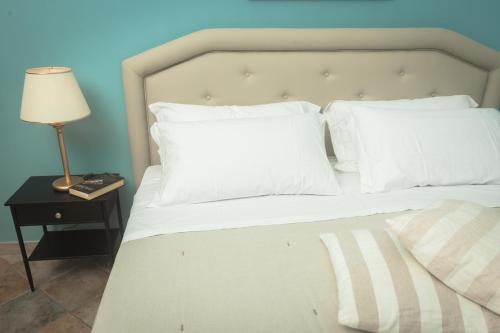 a bed with white pillows and a lamp on a table at Agriturismo Baglio Donnafranca Wine Resort in Marsala