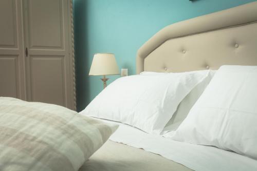 a white bed with white pillows and a lamp at Agriturismo Baglio Donnafranca Wine Resort in Marsala