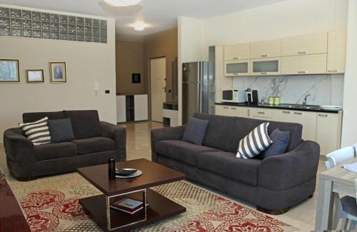 a living room with two couches and a kitchen at Main square apartment in Durrës