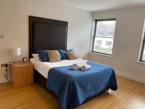 um quarto com uma cama grande e um cobertor azul em 2 bed 2 baths in a central location ☆☆☆☆☆ em Basingstoke