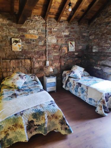 um quarto com 2 camas e uma parede de pedra em Apartamentos C'Ambrosio em La Peral