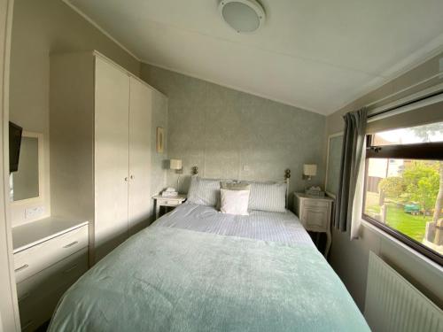a bedroom with a large bed and a window at Rew Farm Country & Equestrian Accommodation - Sunrise Lodge in Melksham