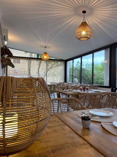 a dining room with tables and chairs and windows at Hôtel L'Escale Coté Port in LʼÎle-Rousse