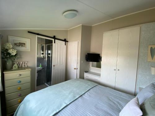 a bedroom with a bed and a dresser at Rew Farm Country & Equestrian Accommodation - Sunrise Lodge in Melksham