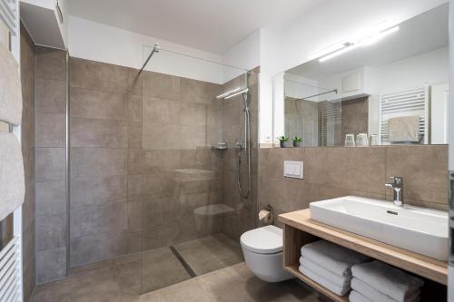 ein Bad mit einer Dusche, einem Waschbecken und einem WC in der Unterkunft Strandhafer Aparthotel in Warnemünde