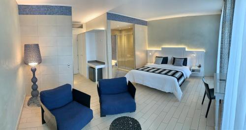a bedroom with a bed and two blue chairs at Continental Parkhotel in Lugano