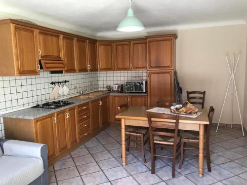 una cocina con armarios de madera y una mesa con sillas. en Appartamento i Tulusan a due passi dalle Langhe, en Narzole