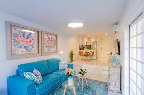 マルベーリャにあるMARBELLA BANUS SUITES - Iris Tropical Garden Banús Suite Apartmentのリビングルーム付きの客室で、青いソファが備わります。