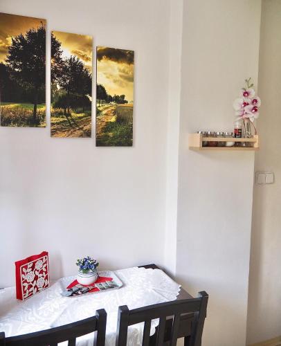 a dining room table with four paintings on the wall at Penzion PANORAMA Janovičky in Broumov