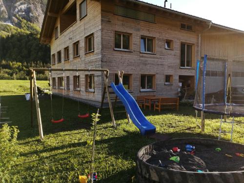 un parque infantil frente a una casa con tobogán en Ferienwohnung Berchtold, en Schnepfau