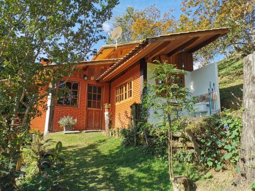 a house on a hill with a yard at Chalé Mauá Conforto e Arte in Visconde De Maua