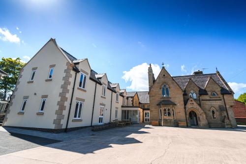 a large white building with a church in the background at The Lemon Tree in Wrexham