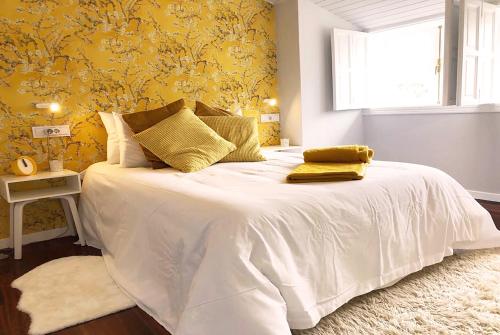 1 dormitorio con 1 cama blanca grande y papel pintado de color amarillo en Yellow Home, en Santiago de Compostela