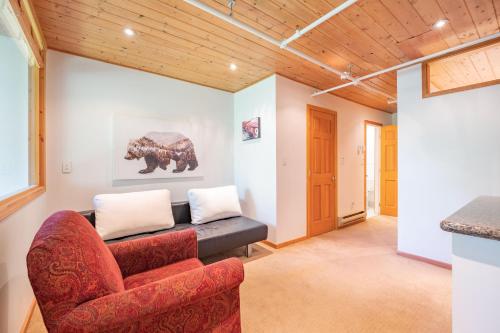 a living room with a red couch and a painting of a bear at Powderhorn by Outpost Whistler in Whistler