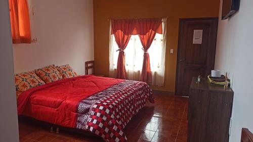 a bedroom with a red bed and a window at Hostería La Chorrera in Quito