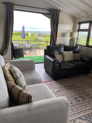a living room with couches and a couch and a table at Rew Farm Country & Equestrian Accommodation - Sunrise Lodge in Melksham