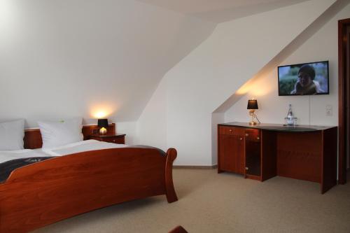 um quarto com uma cama e uma secretária com uma televisão em Landhaus am Golfpark em Langenhagen