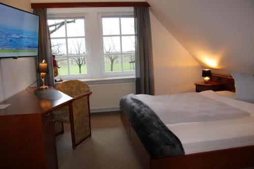 a hotel room with a bed and a desk and window at Landhaus am Golfpark in Langenhagen
