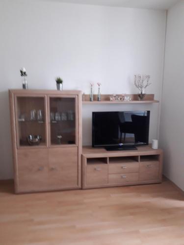 un centro de entretenimiento de madera con TV de pantalla plana en Ferienwohnung Chemnitz - Kaßberg en Chemnitz