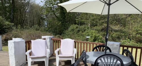 einen Tisch und Stühle mit einem Sonnenschirm auf einer Terrasse in der Unterkunft Whitestone Cottage in Turnberry