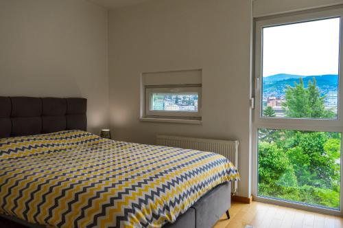 a bedroom with a bed and a large window at Panorama Apartment in City-Centre in Sarajevo