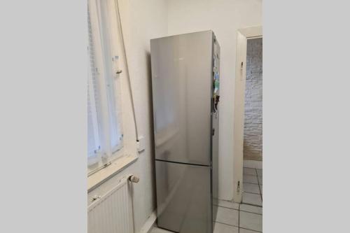 einem Kühlschrank aus Edelstahl in einer Küche neben einem Fenster in der Unterkunft Charmantes helles Zimmer zentrumnah und naturnah in Göppingen