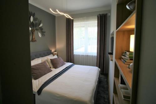 mała sypialnia z łóżkiem i oknem w obiekcie Otium Wellness Apartmanház w mieście Balatonakarattya