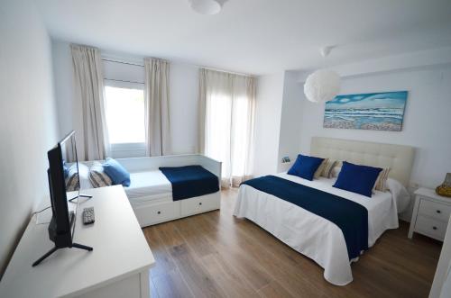 1 dormitorio con 2 camas y escritorio con TV en Golive De Mar en Cambrils