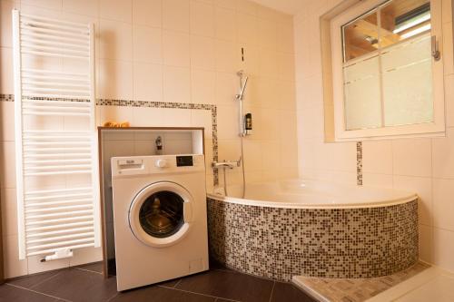 a bathroom with a tub and a washing machine at Gasthof Klug zum Ehrensepp in Modriach