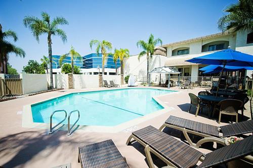 a swimming pool with chairs and a table and umbrella at Hotel d'Lins Ontario Airport in Ontario