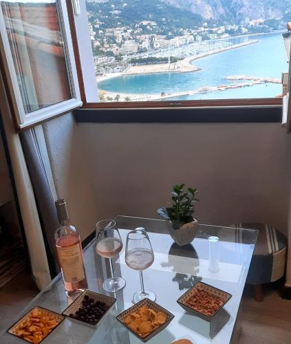 una mesa con dos copas de vino y una ventana en MENTON, centre historique, vue mer, en Menton